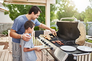 Father teaching son to grill on a gas grill how to choose a grill