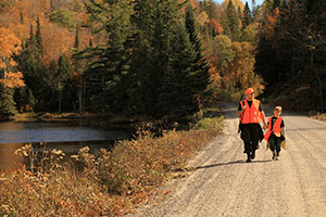 Pair of Hunters Wearing Orange Safety Gear While Walking