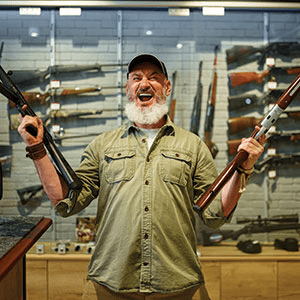Man Holding Two Rifles at a Gun Store