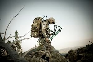 Man Wearing Camo and Hiking With Compound Bow