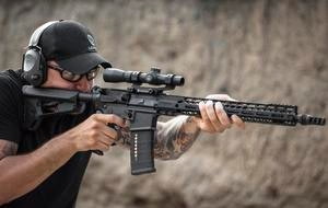 Man Aiming Through Rifle Scope Mounted on AR 15